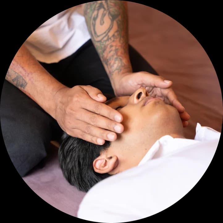 Practitioner's hands resting gently on a recipient's head during Reiki